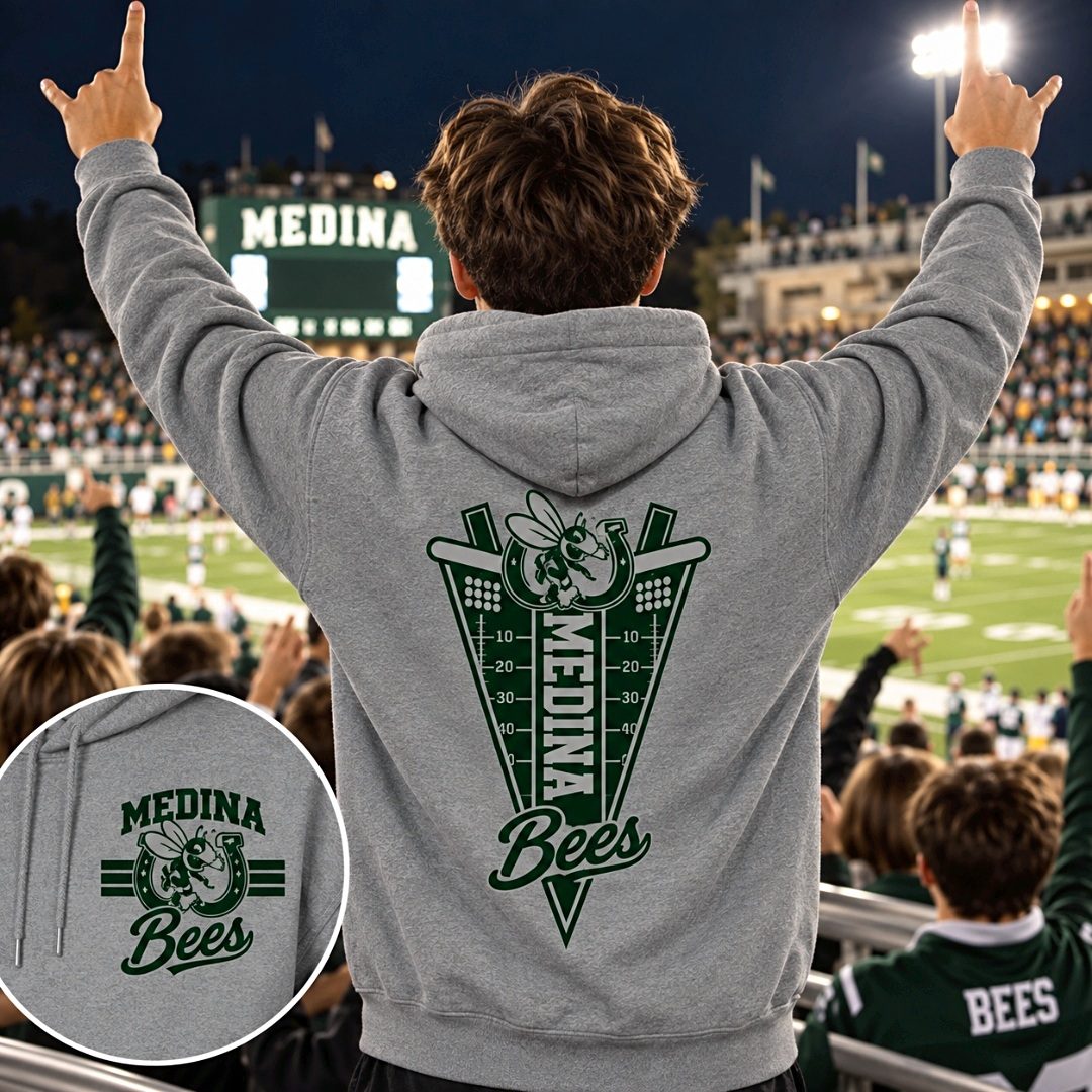 Young fan in the stands wearing a grey Medina Bees football hoodie with arms raised